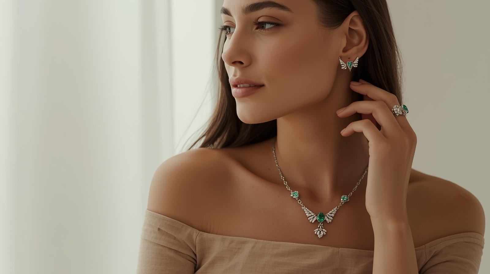 A white-gold necklace and matching earring with a wing motif, set with emeralds and diamonds.